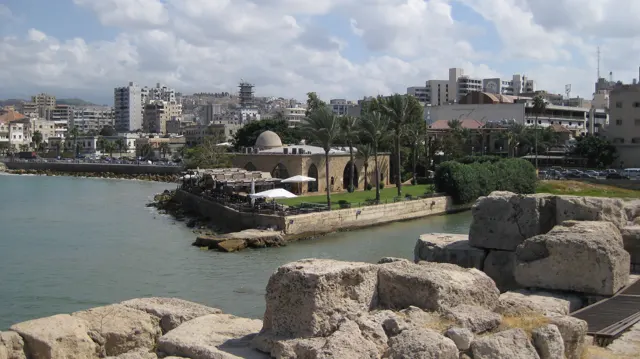 Large weathered stone blocks fill the foreground above water and a planted waterfront area.