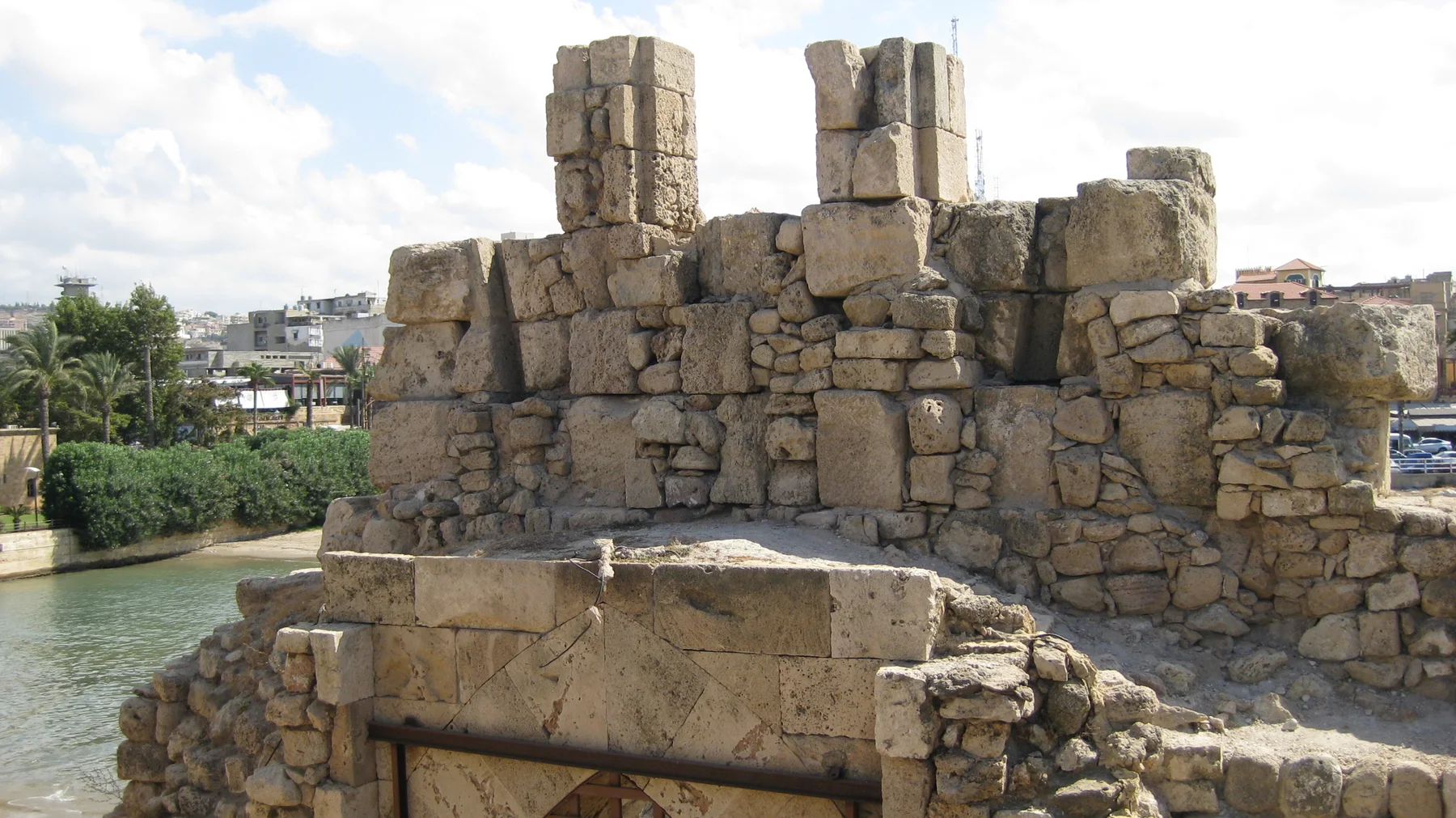 Uneven masonry walls and upright stone blocks stand above the water within the sea castle.