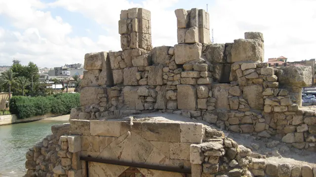 Uneven masonry walls and upright stone blocks stand above the water within the sea castle.