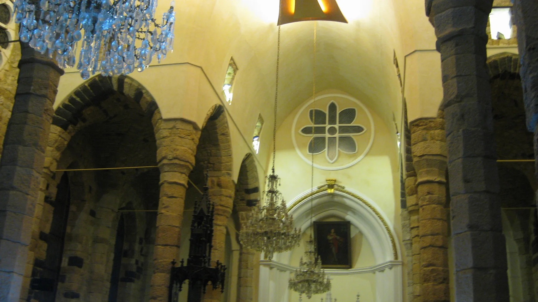 Stone columns and arches frame a brightly lit church entrance beneath a clover-shaped window.