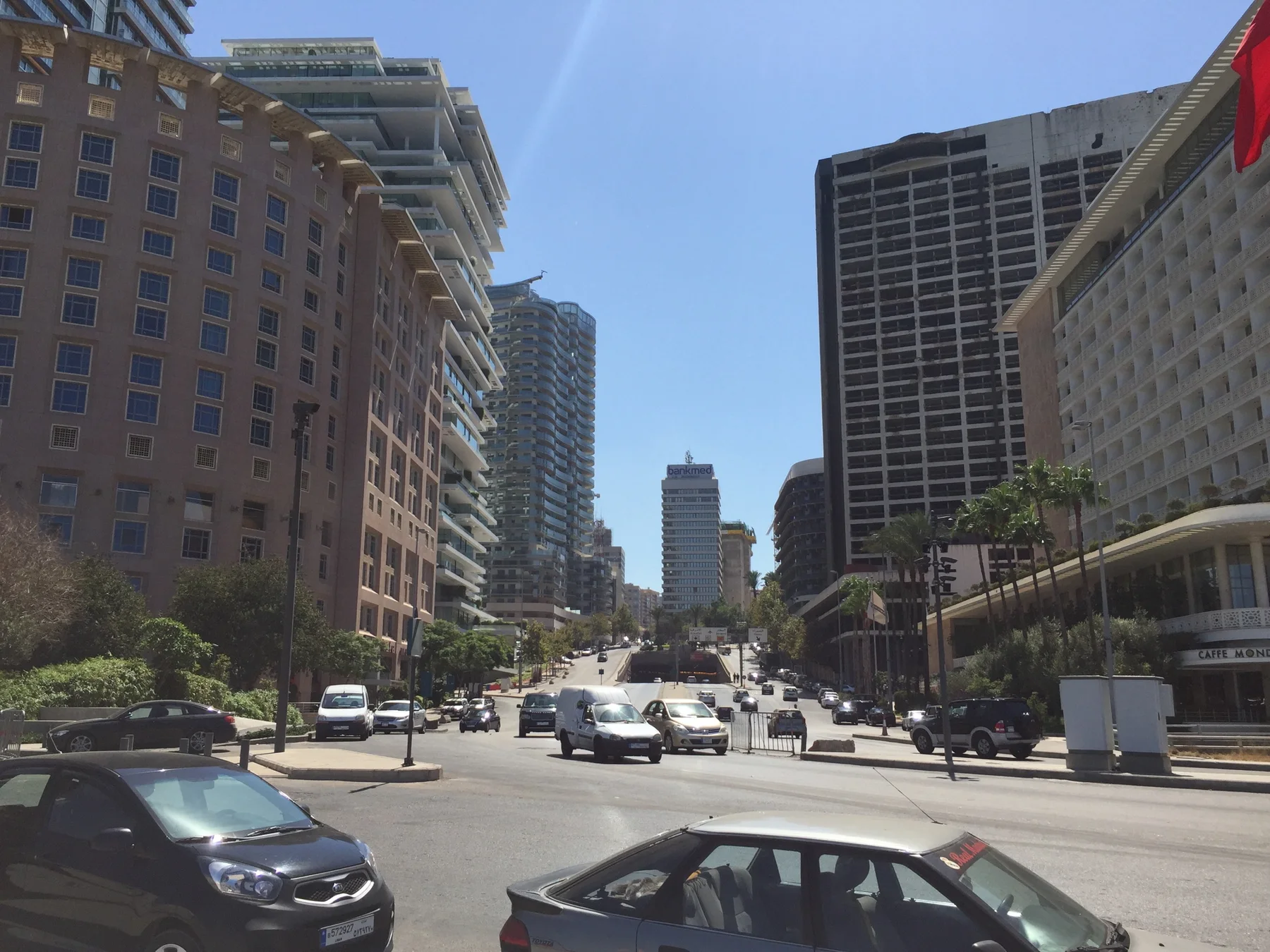 Traffic crosses a broad urban junction surrounded by tall buildings and rows of windows.