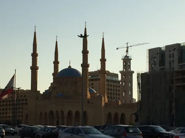 A large blue dome and four slender minarets rise above parked cars and surrounding buildings.
