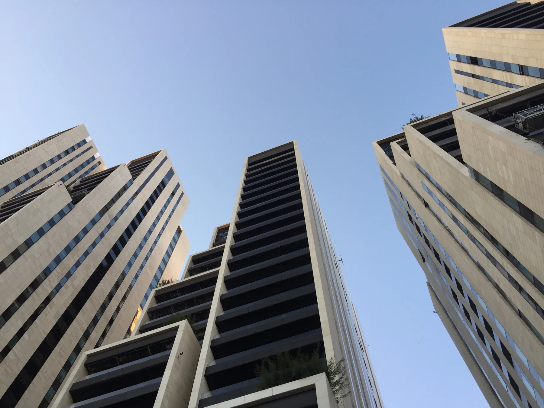 Several modern towers converge in an upward view, with projecting balconies and vertical concrete lines.