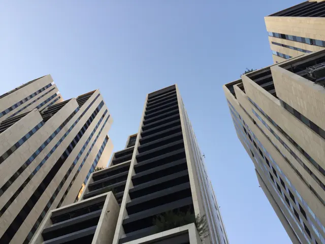 Several modern towers converge in an upward view, with projecting balconies and vertical concrete lines.