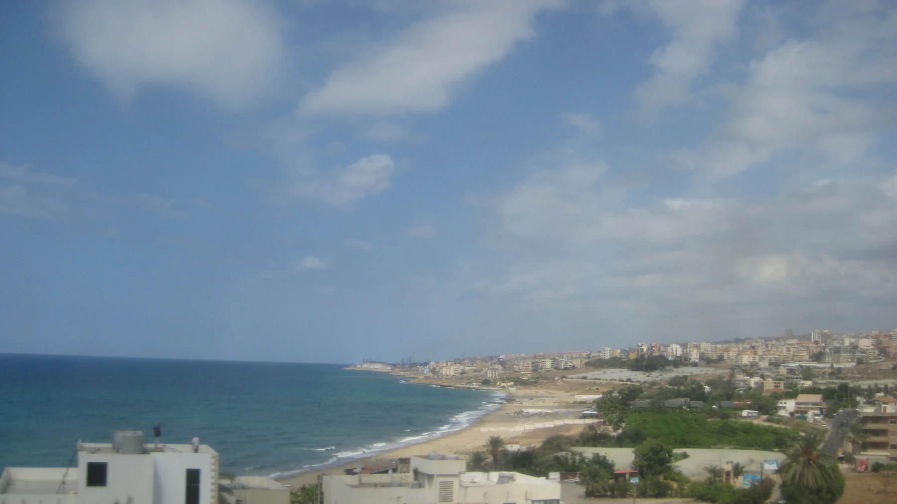 The shoreline curves beneath a hillside covered with pale buildings and scattered greenery.