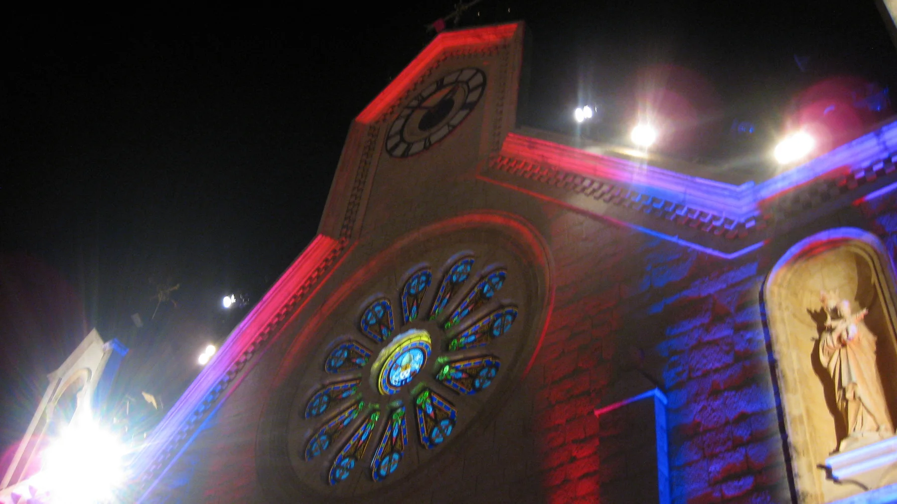 An angled view shows a brightly lit circular church window and a statue niche edged with red and blue lighting.