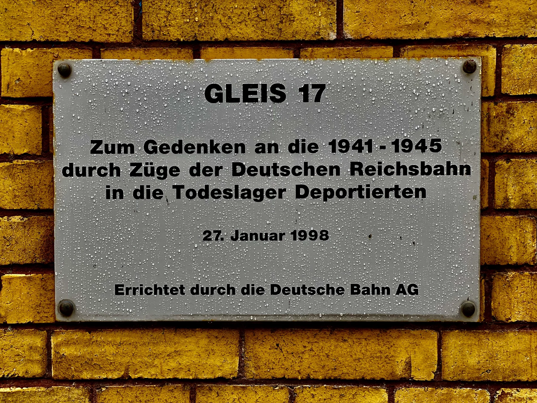 A metal plaque headed Gleis 17 is fixed to a brick wall, commemorating people deported by Deutsche Reichsbahn trains between 1941 and 1945.