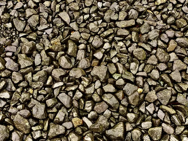 A close-up fills the frame with angular railway ballast stones in grey and brown tones.