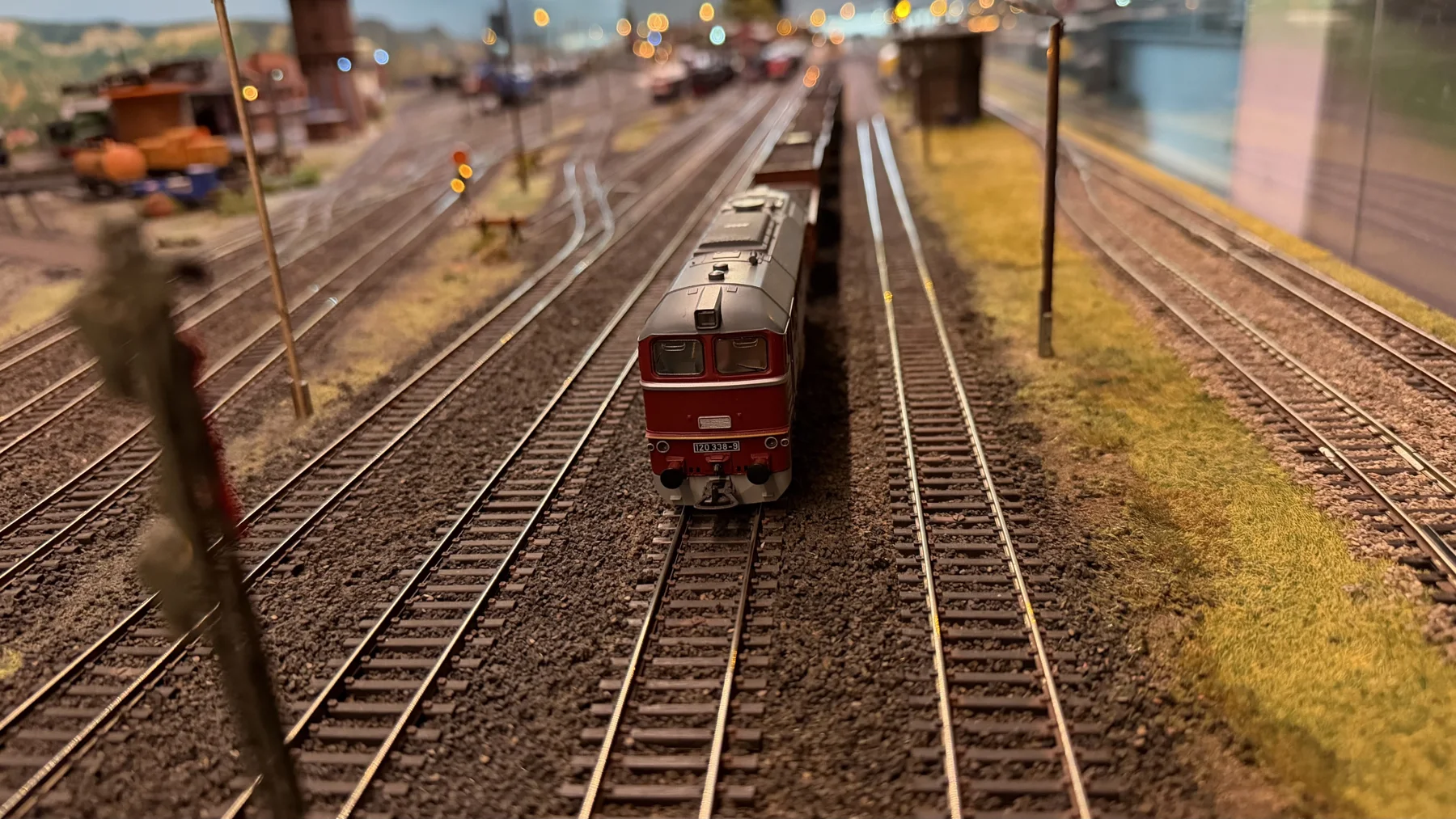 A dark red model locomotive faces the camera on one of several parallel tracks.