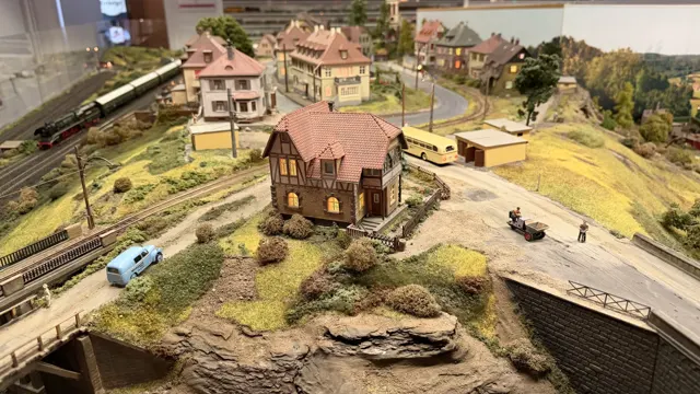 Miniature houses, roads and trees sit above curving railway tracks and a road bridge.