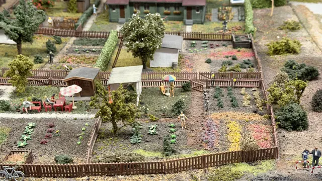 Tiny garden plots, sheds and fences form a detailed miniature allotment scene.