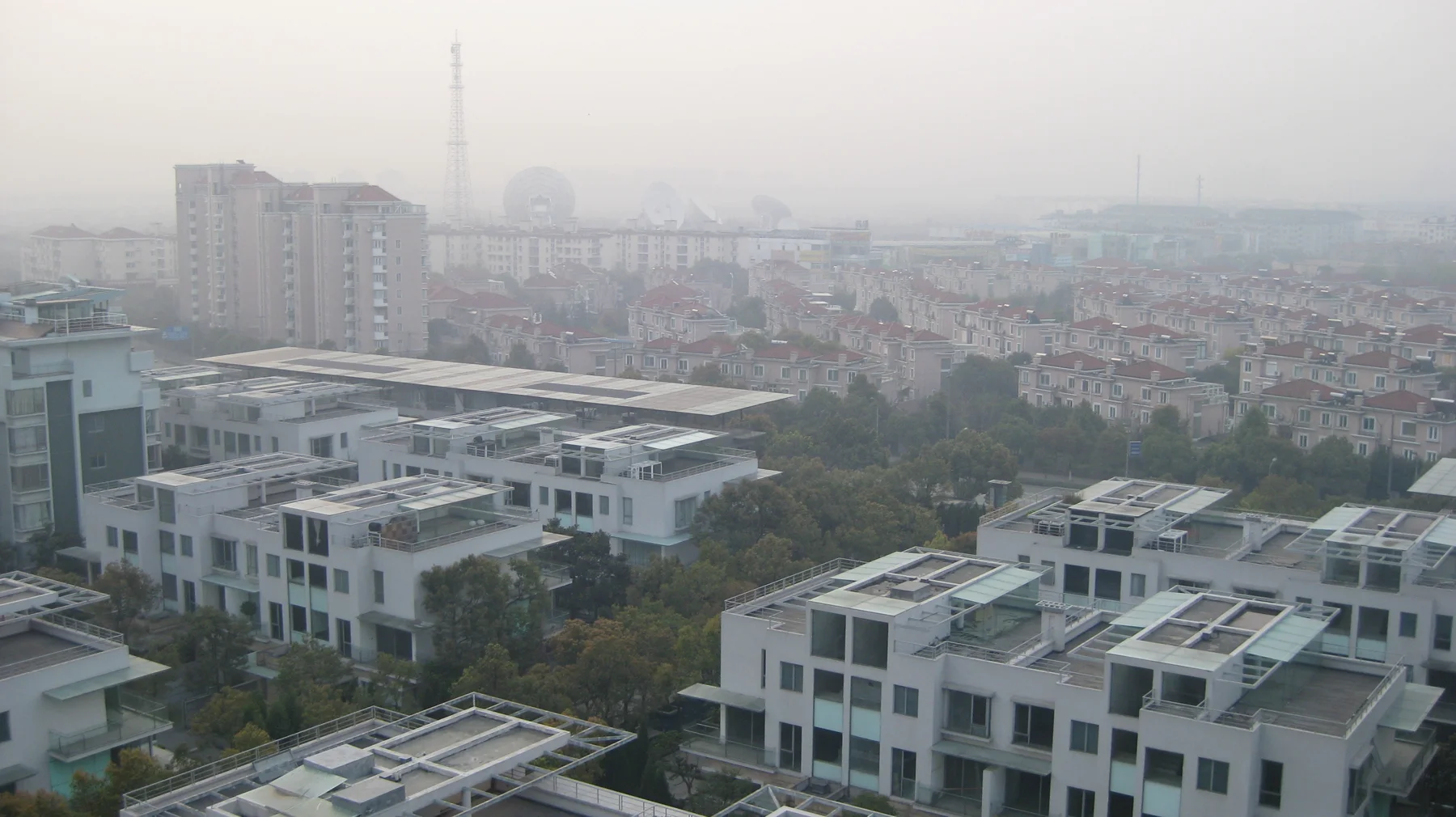 White flat-roofed buildings occupy the foreground, with a dense neighbourhood and taller blocks behind.