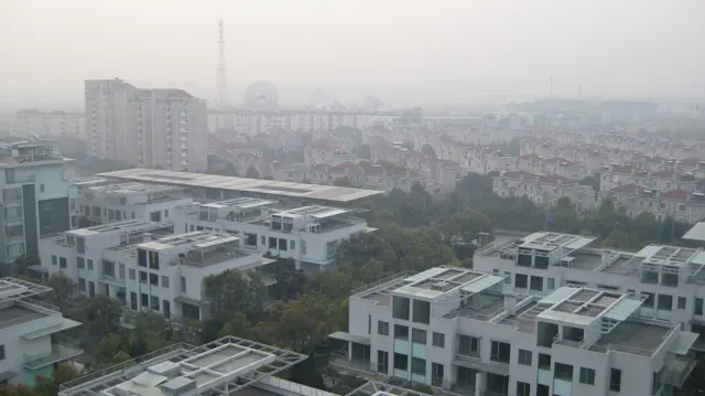 White flat-roofed buildings occupy the foreground, with a dense neighbourhood and taller blocks behind.