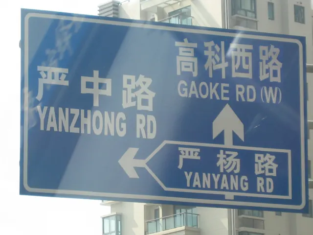 A blue road sign displays Chinese and English street names with white directional arrows.