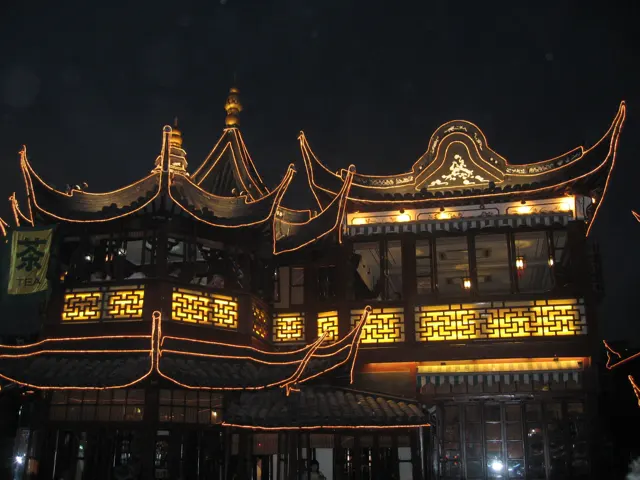 Curved rooflines and patterned windows glow gold against a dark evening sky.