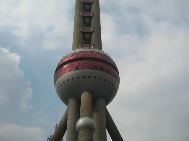 A close upward view shows a large pink-banded sphere supported by massive columns beneath the tower shaft.