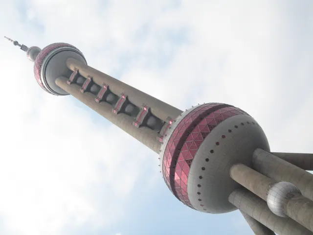 The tower rises diagonally from broad supporting columns through pink spherical sections towards a slender spire.
