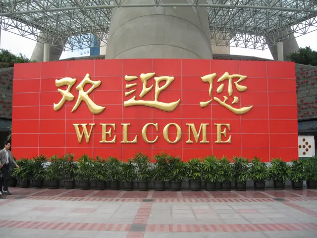 Gold Chinese characters and the word Welcome appear on a large red sign beneath a tall structural interior.