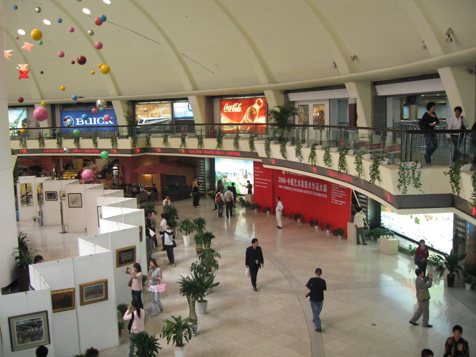 Visitors move through a bright indoor concourse beneath a curved upper gallery and hanging star decorations.