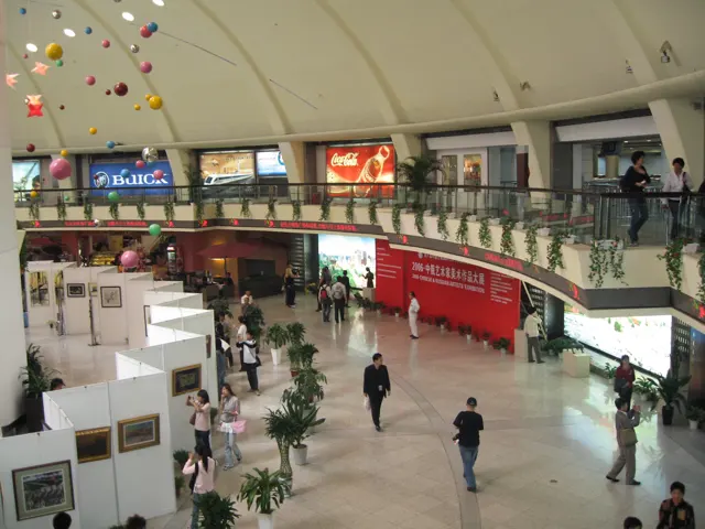 Visitors move through a bright indoor concourse beneath a curved upper gallery and hanging star decorations.