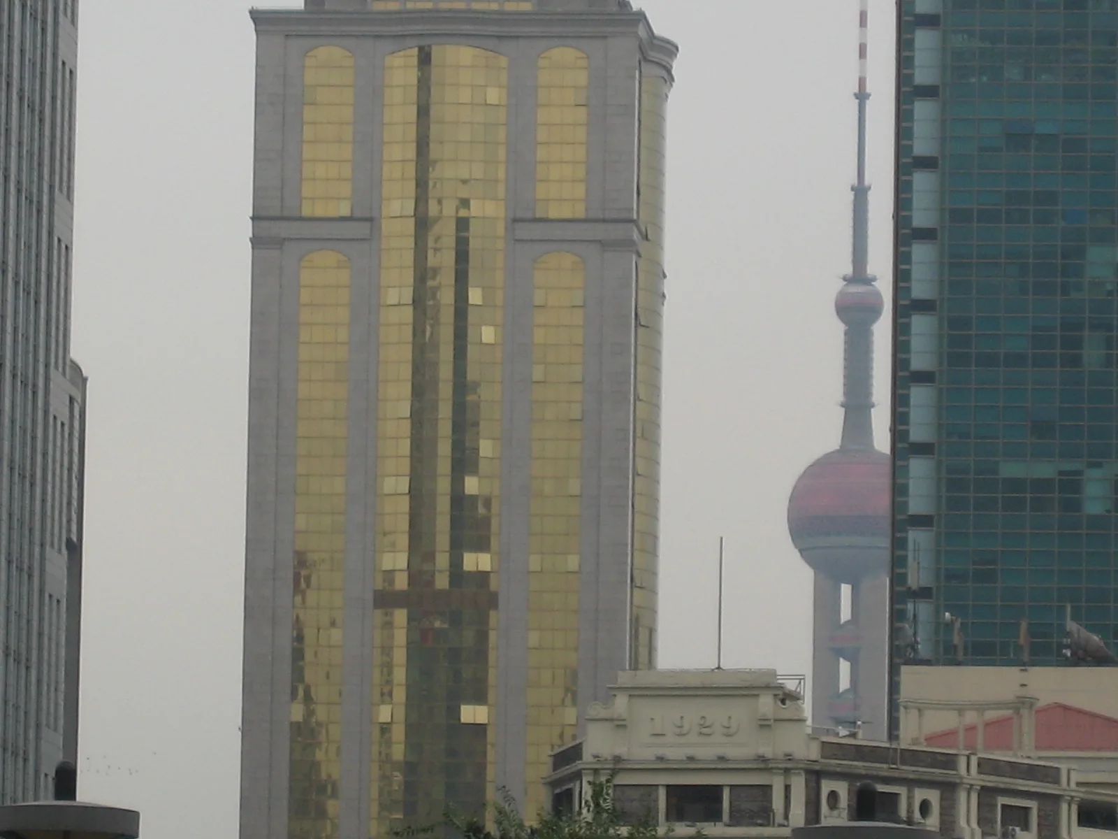 A gold-toned high-rise and a spherical-section tower appear between neighbouring facades in a compressed city view.