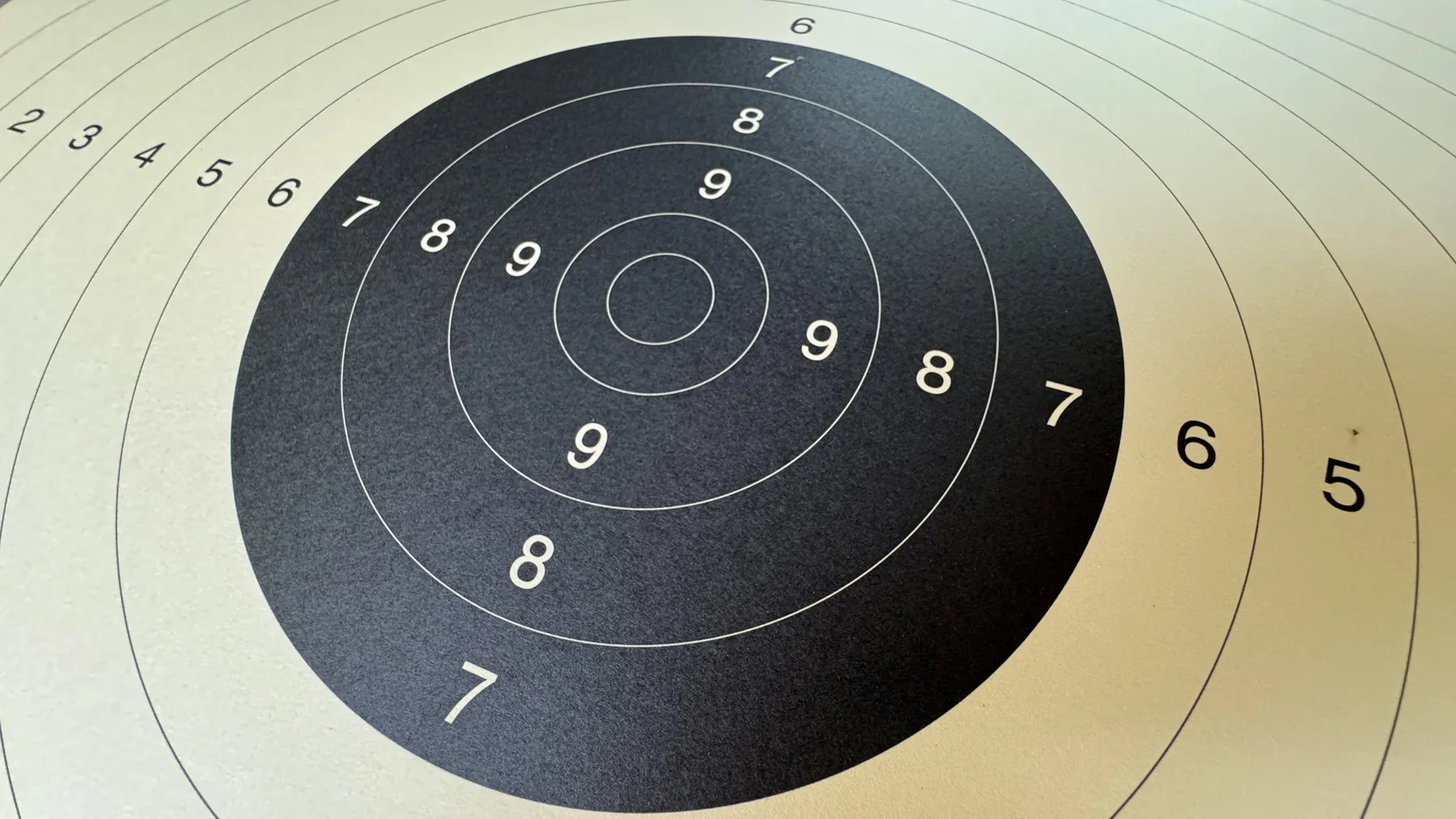A black target centre fills much of the frame, bordered by cream paper and successive scoring rings.