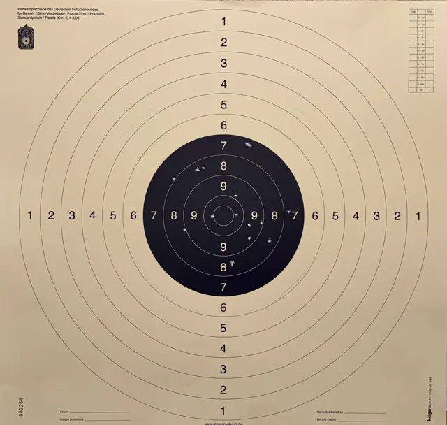 A square cream-coloured target sheet with a small black centre, concentric rings and rows of scoring numbers.