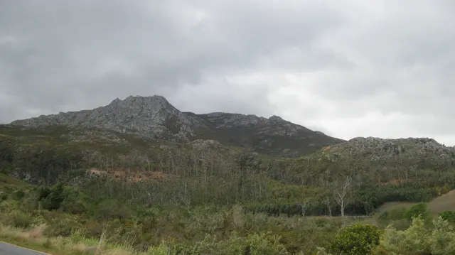 Scrub and cultivated rows spread below a low rocky ridge.