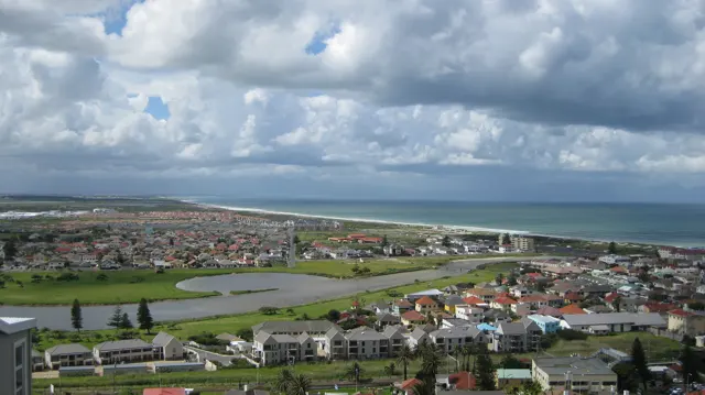 Green playing fields interrupt dense town roofs near the ocean.