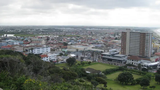 A tall rectangular building rises above low coastal development.