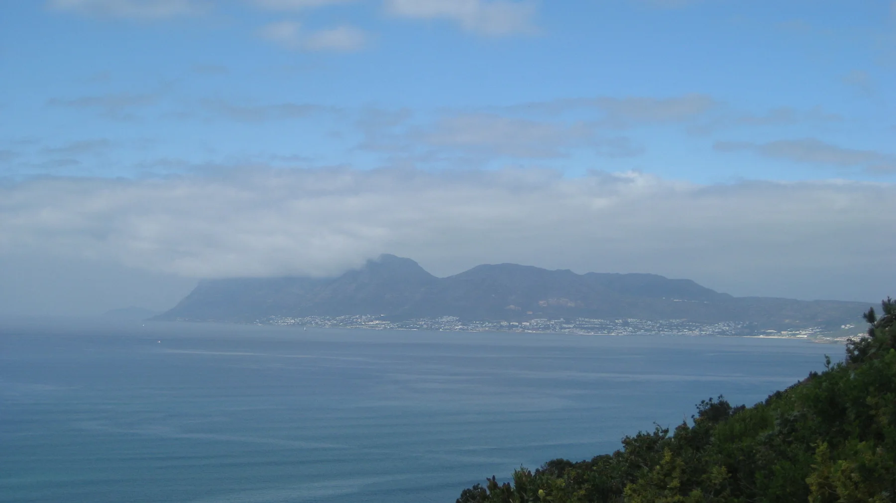 A distant mountain coastline fades into haze across blue water.