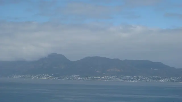 A mountain range forms a hazy blue silhouette across the bay.