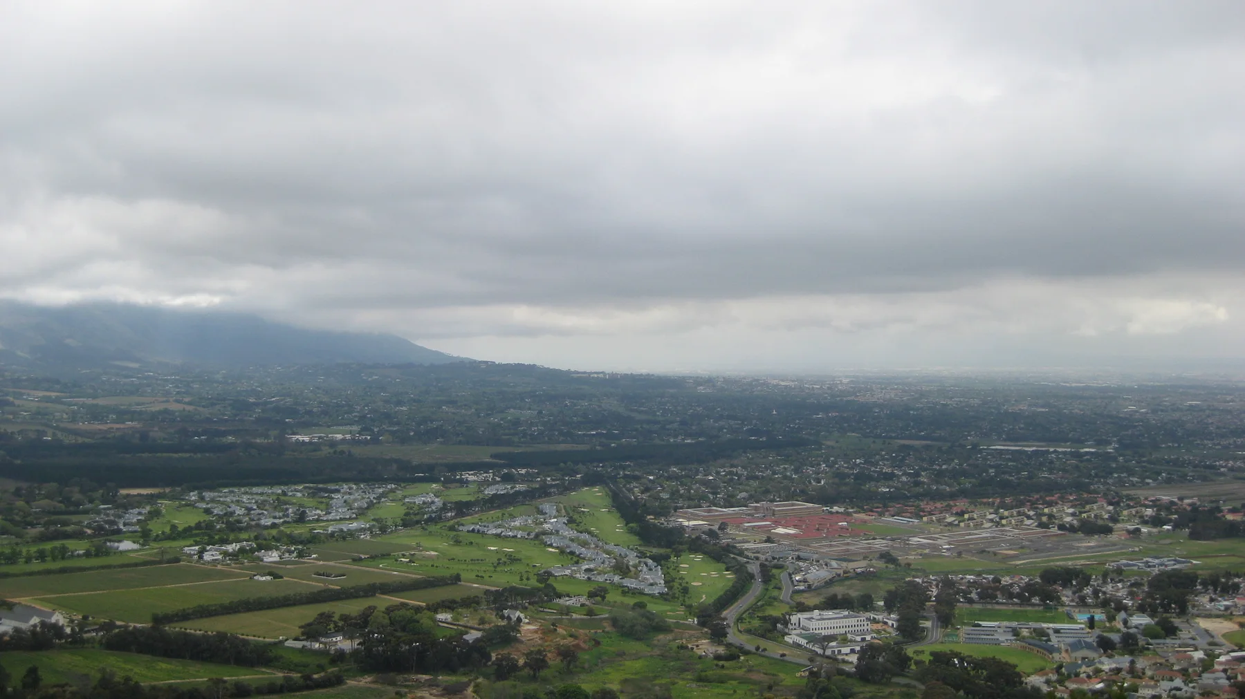 Green fields and buildings spread through a broad valley under low clouds.