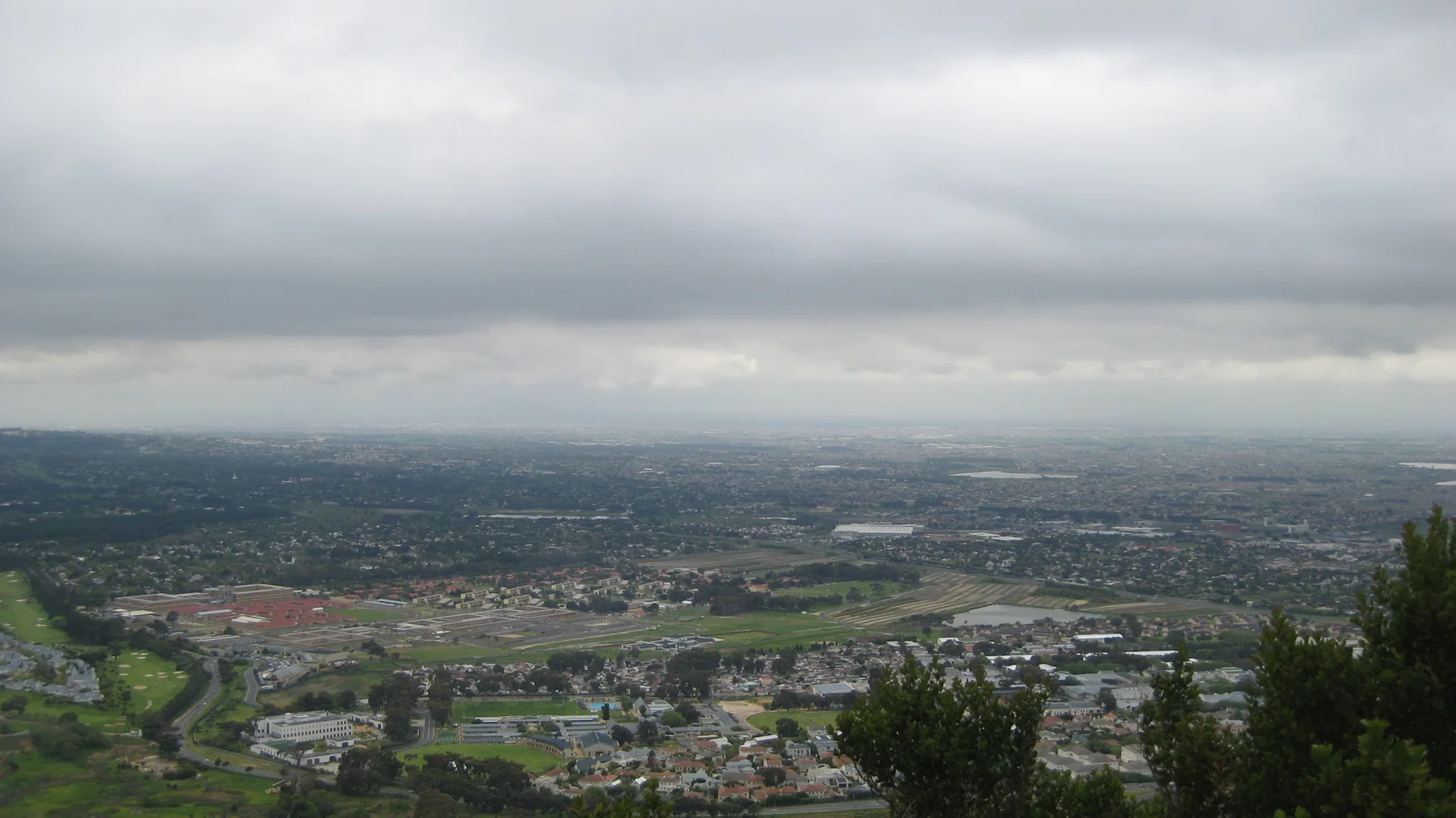 Buildings and green spaces spread across a valley beneath a low cloud ceiling.
