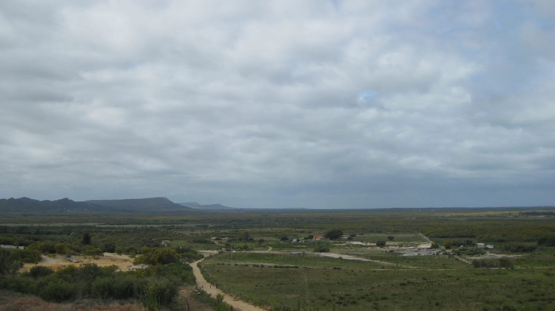A pale track cuts through low vegetation toward distant hills.