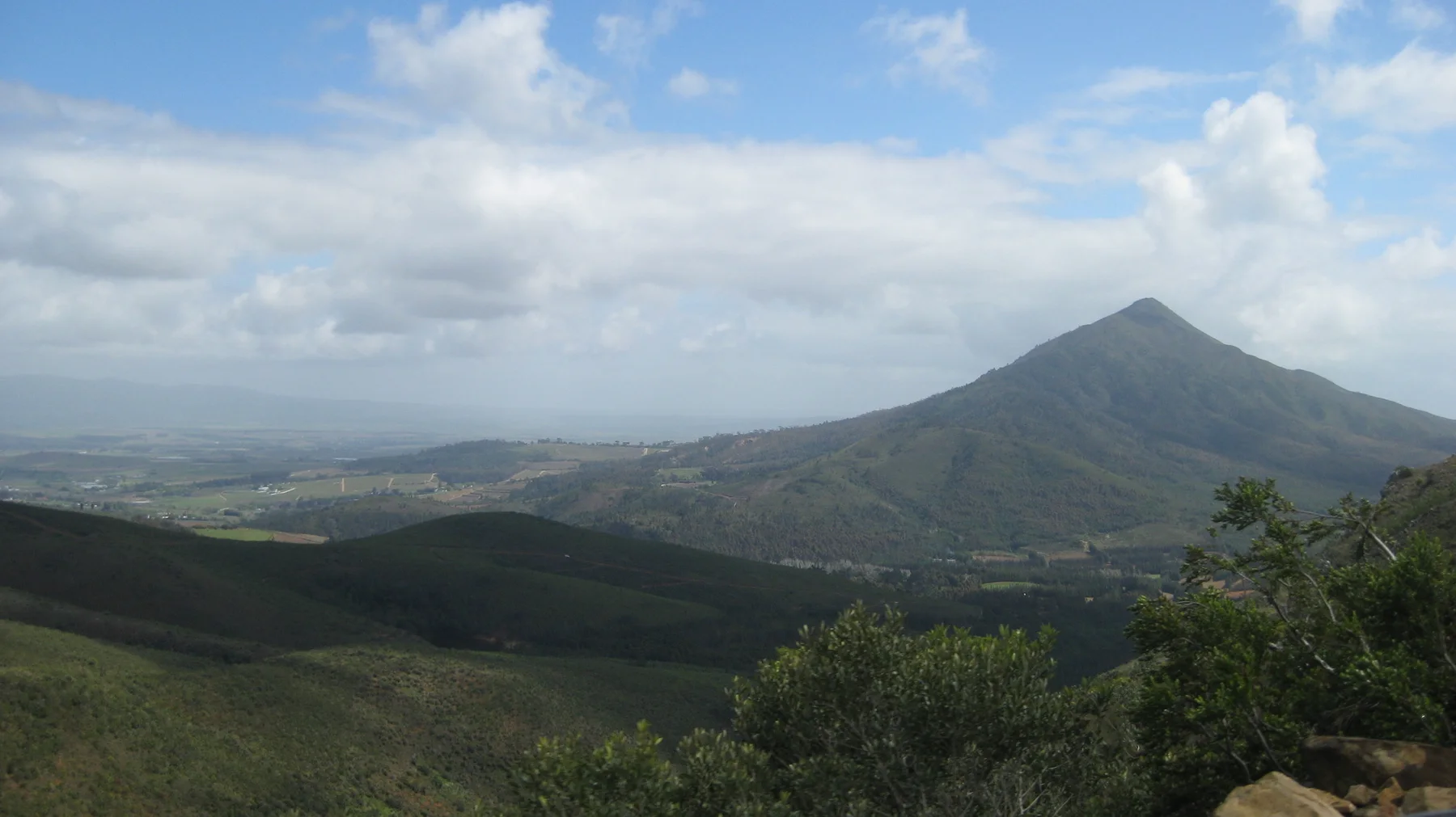 A pointed mountain rises beyond rolling green slopes.