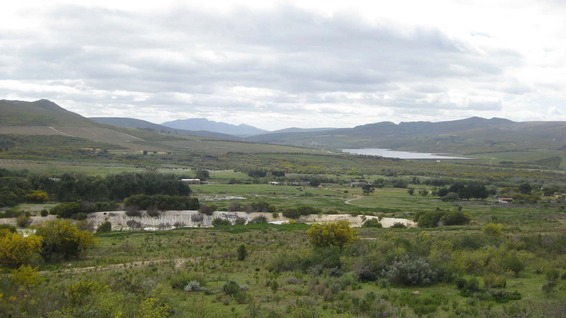 Green cultivated land stretches toward a pale strip of water between hills.