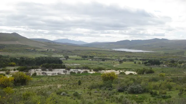 Green cultivated land stretches toward a pale strip of water between hills.