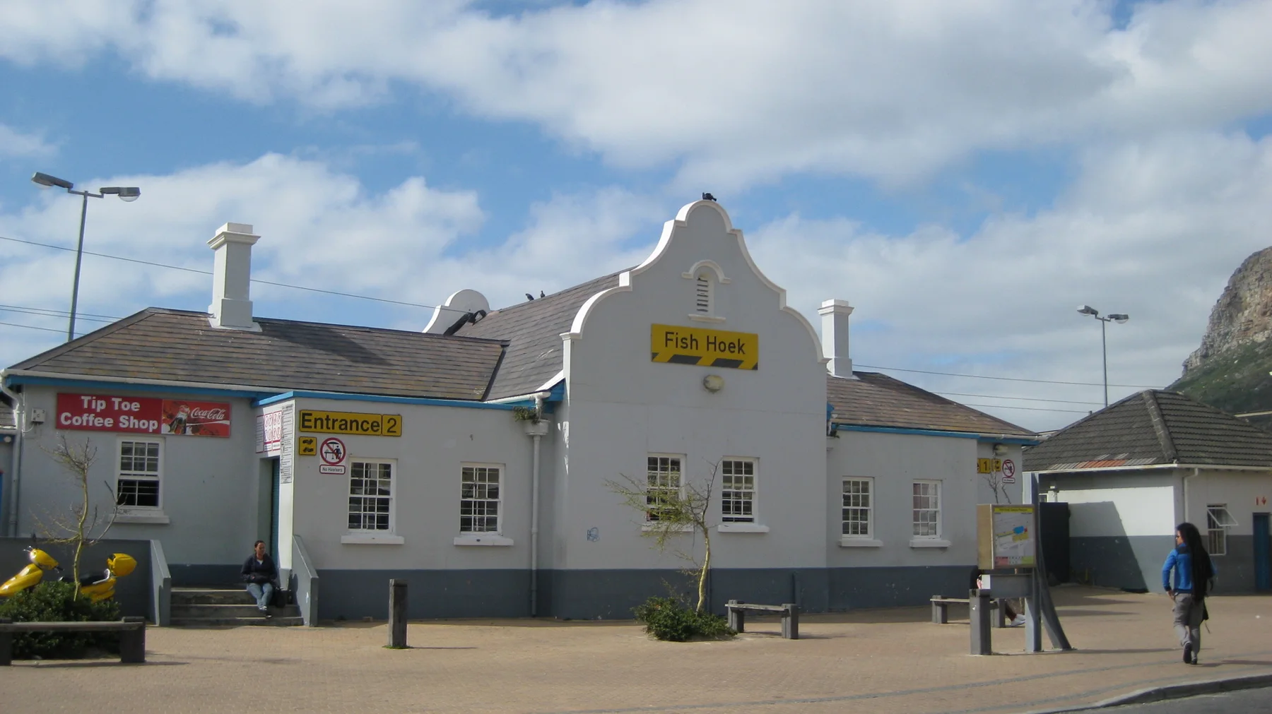 A white roadside building has a curved gable and a row of small windows.