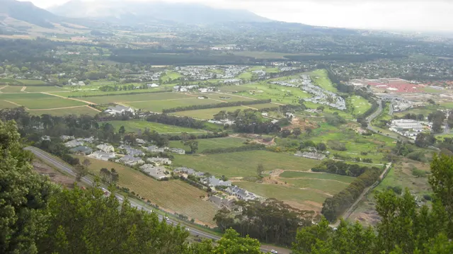 Green fields, houses and winding roads fill an elevated valley view.
