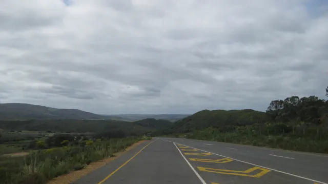 Yellow road markings lead through open country beneath layered clouds.