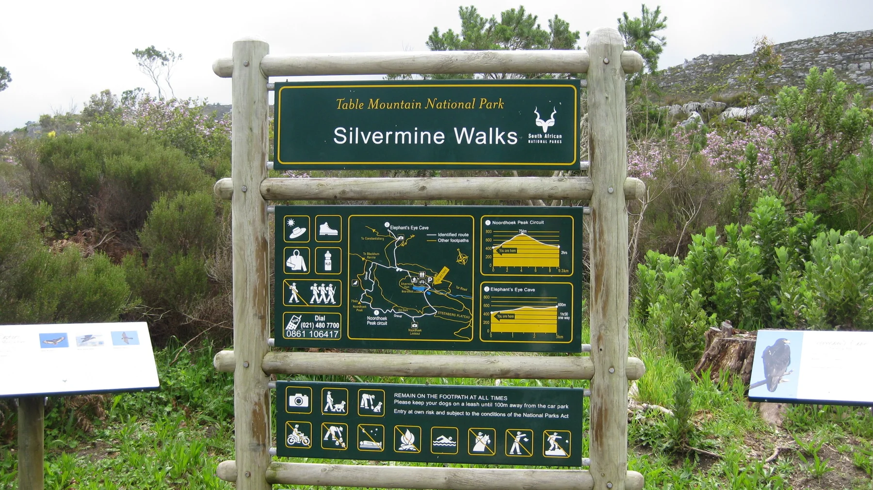 A wooden-framed Silvermine Walks information board stands among shrubs.