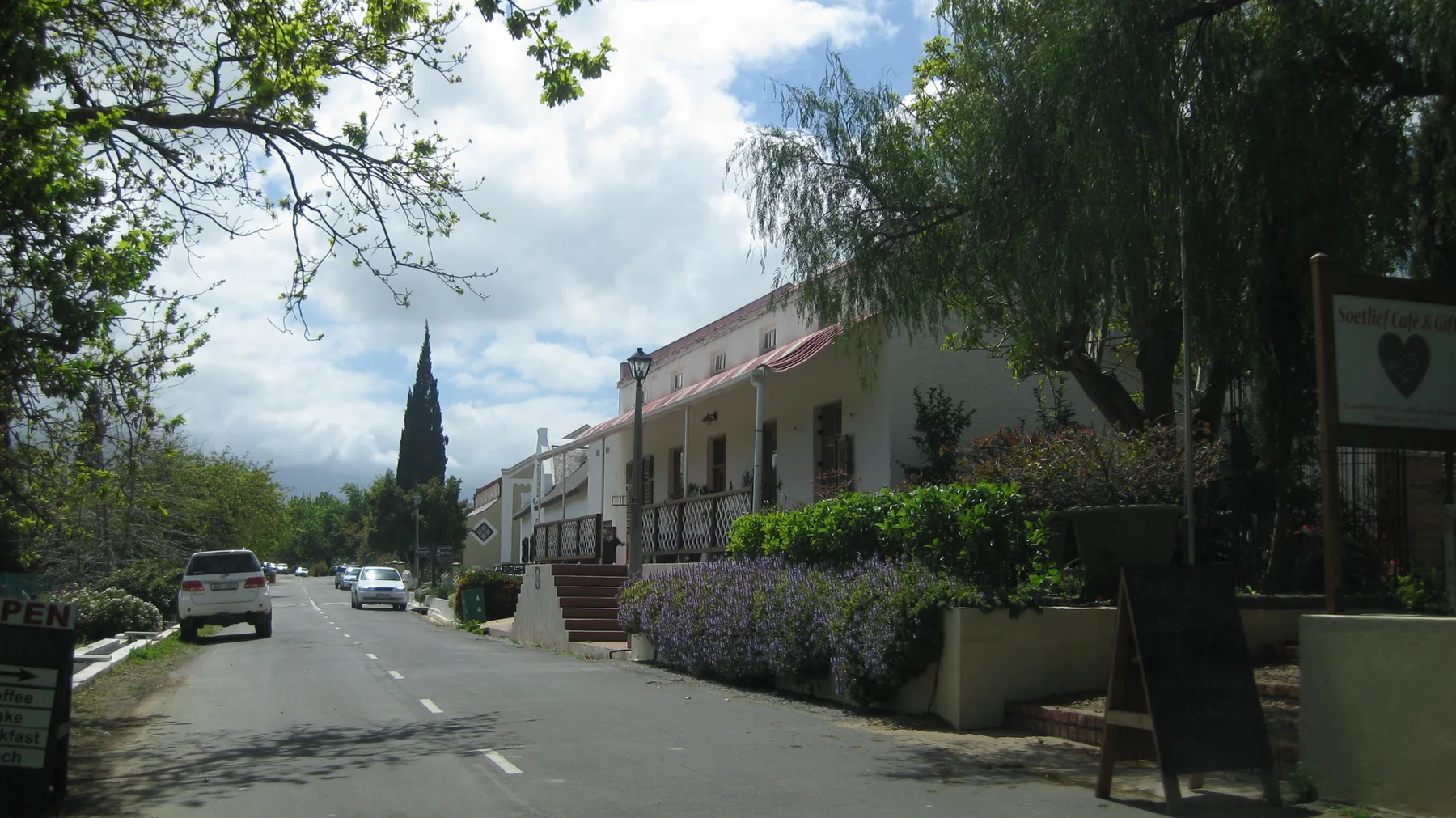 A church spire rises beyond a shaded street lined with pale buildings.