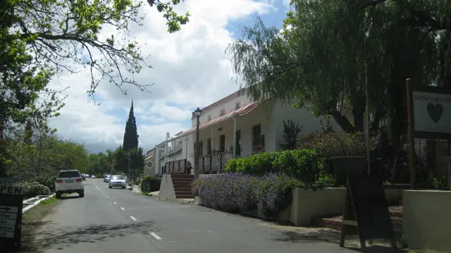 A church spire rises beyond a shaded street lined with pale buildings.