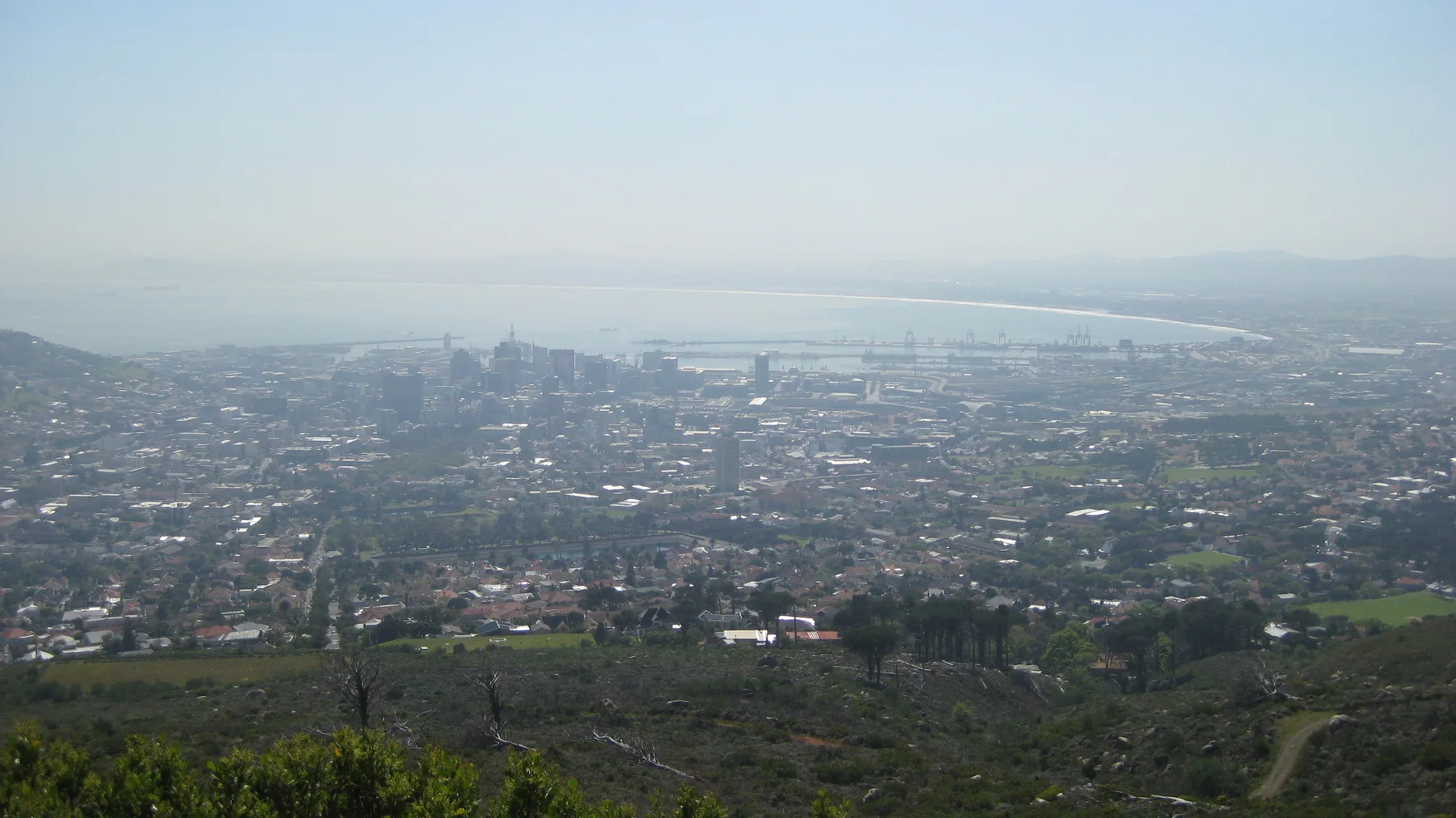 Dense development stretches toward distant water beneath a hazy sky.