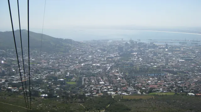 Dark cable lines descend across a high view of city and bay.
