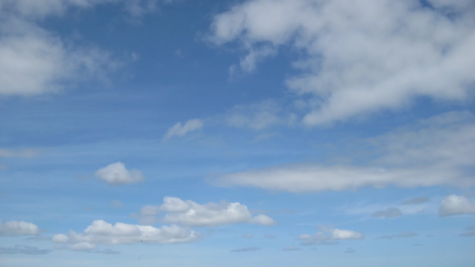 White cloud patches drift across a broad blue sky.