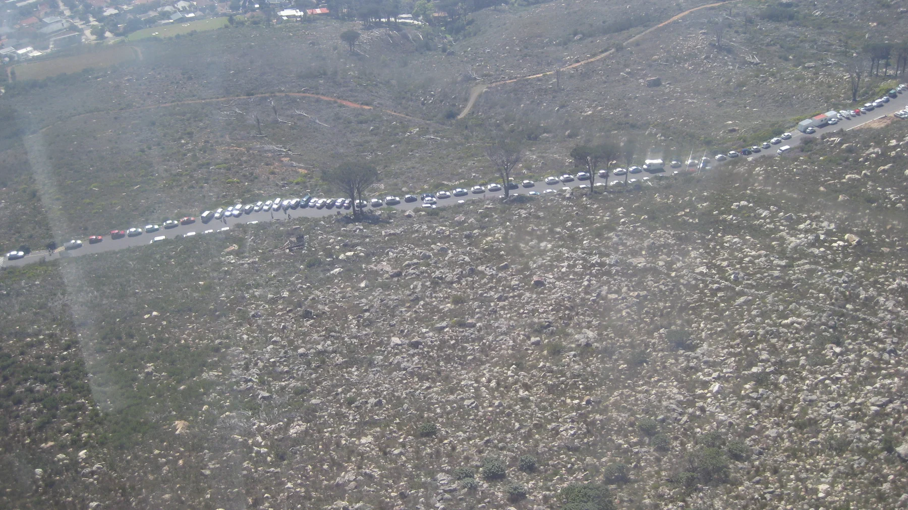 A winding road crosses a broad rocky mountainside seen from above.