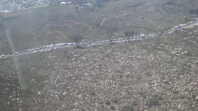 A winding road crosses a broad rocky mountainside seen from above.