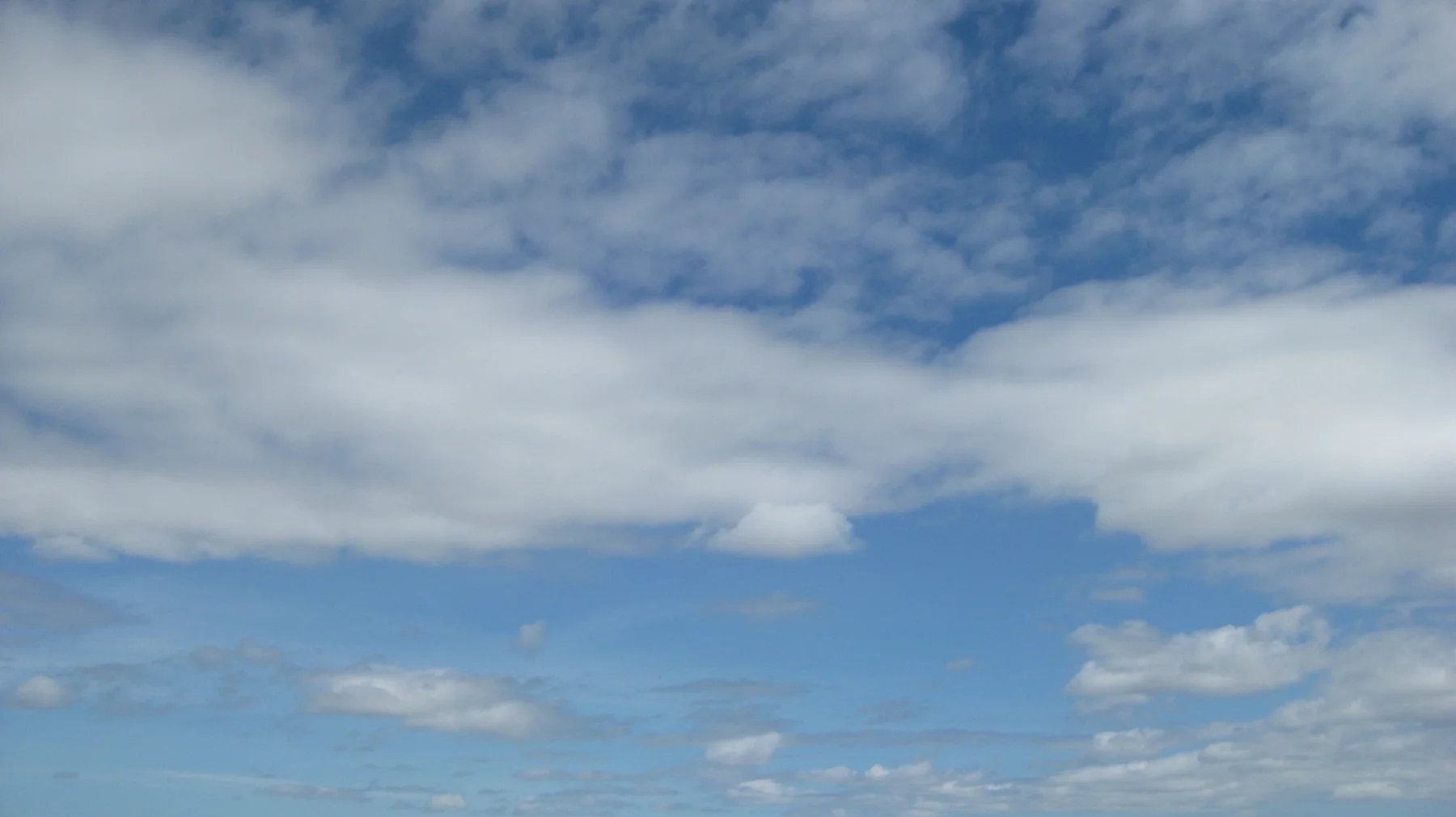 Thin white clouds stretch across a blue sky.